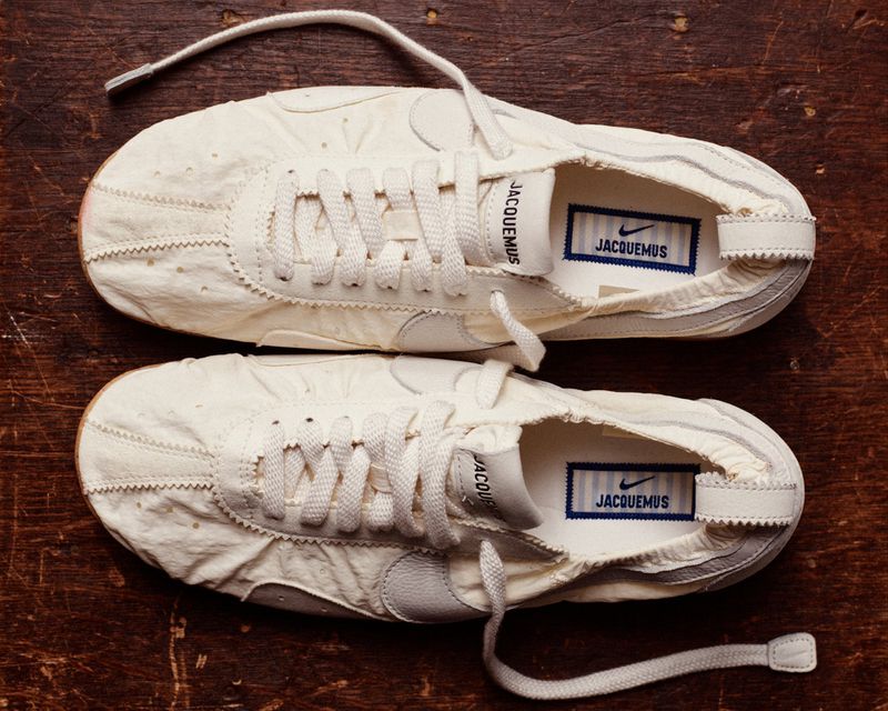 Two pairs of unbranded white textile running shoes with laces, on a dark brown textured surface, displaying athletic footwear fashion.