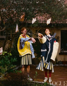 Two male models in layered designer outfits throwing paper letters in a garden setting, photographed by Michelle Du Xuan for Vogue China Men.
