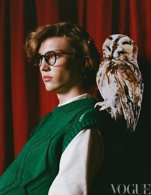 Young model in glasses and green knit vest with an illustrated owl perched on shoulder