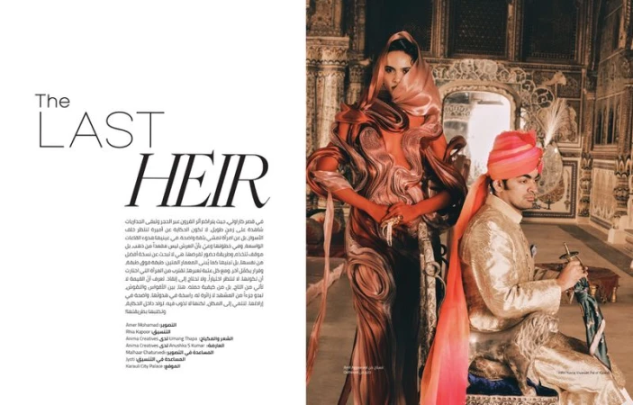 Editorial fashion shot of a woman in a patterned gown and head covering standing next to a man in traditional Indian attire indoors.