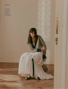 Model seated on a wooden floor wearing a long white skirt and taupe top, captured in natural light for Yo Dona Spain.