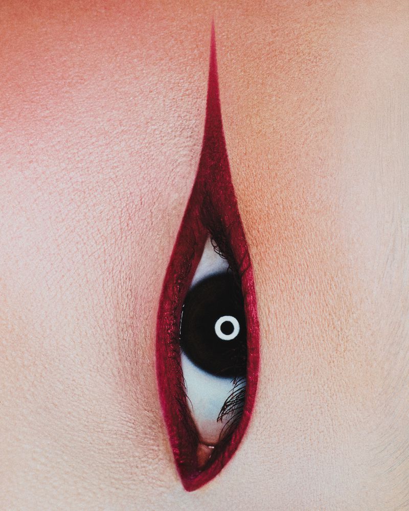 Close-up on a person's eye with a striking red makeup design, creating a dramatic and artistic visual statement. Beauty concept.