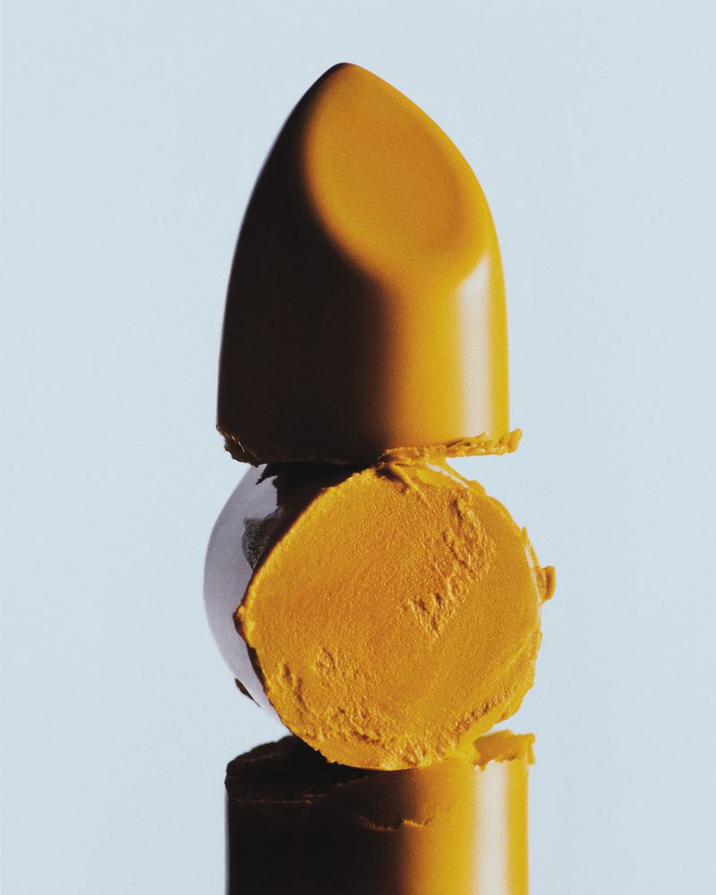 Close-up studio shot of a stacked golden lipstick, showcasing its form, texture, and color against a bright background, beauty concept.