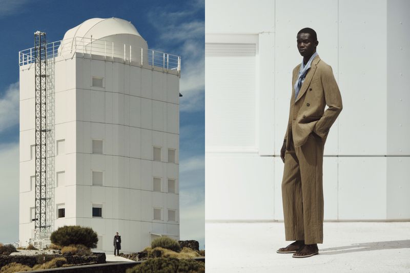 Fashion shot featuring a Black male model in a brown suit on the right and an observatory building on the left, outdoors.