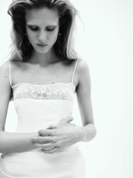 Model Vakare Steputyte wearing a white lace-trimmed slip dress against a plain background