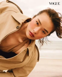 Model wearing a tan jacket leaning toward the camera against a soft outdoor background for Vogue Thailand June 2025 Beauty Cover