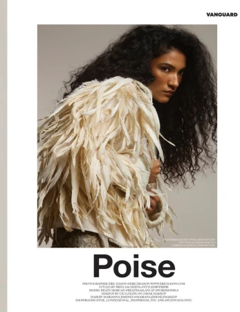 Fashion shot of a South Asian model with voluminous black curly hair wearing a white feather jacket in a photo studio setting.