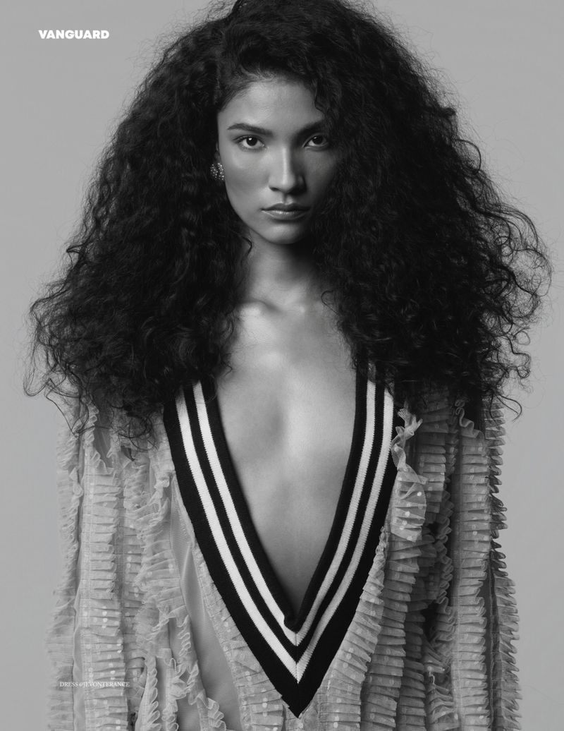 Black and white portrait of a woman with curly hair wearing a deep V-neck sweater with black and white stripes and a fringed jacket.