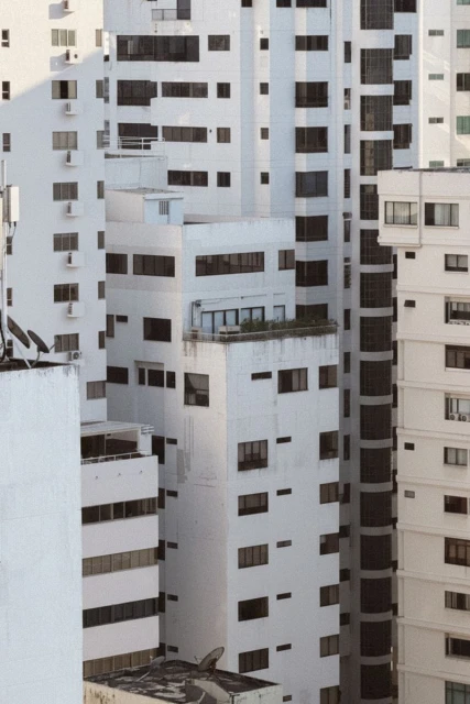 Aerial view of a cluster of tall white apartment buildings with multiple windows, showing urban architecture and density.