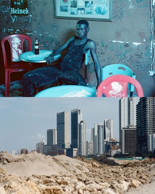 Indoor shot of a Black male model in a sparkling jumpsuit seated at a table, with a beach-city background featuring high-rise buildings.