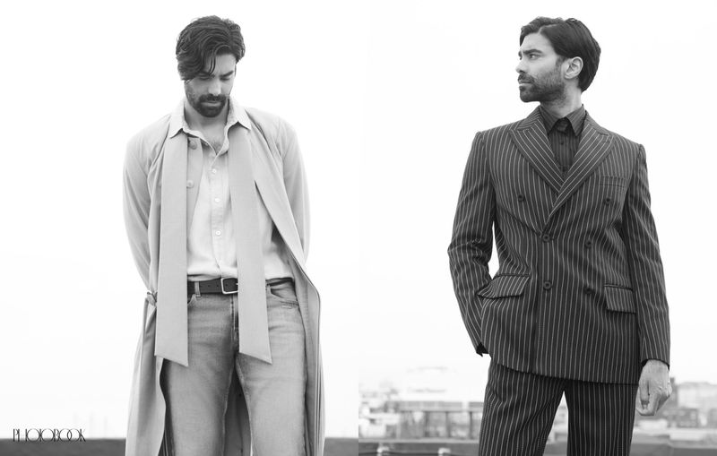 Black and white portrait of two adult men on a rooftop, one in a trench coat and the other in a pinstripe suit, against a bright background.
