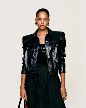 Model wearing a glossy black leather jacket and dark skirt against a plain studio background for the Zara lookbook.