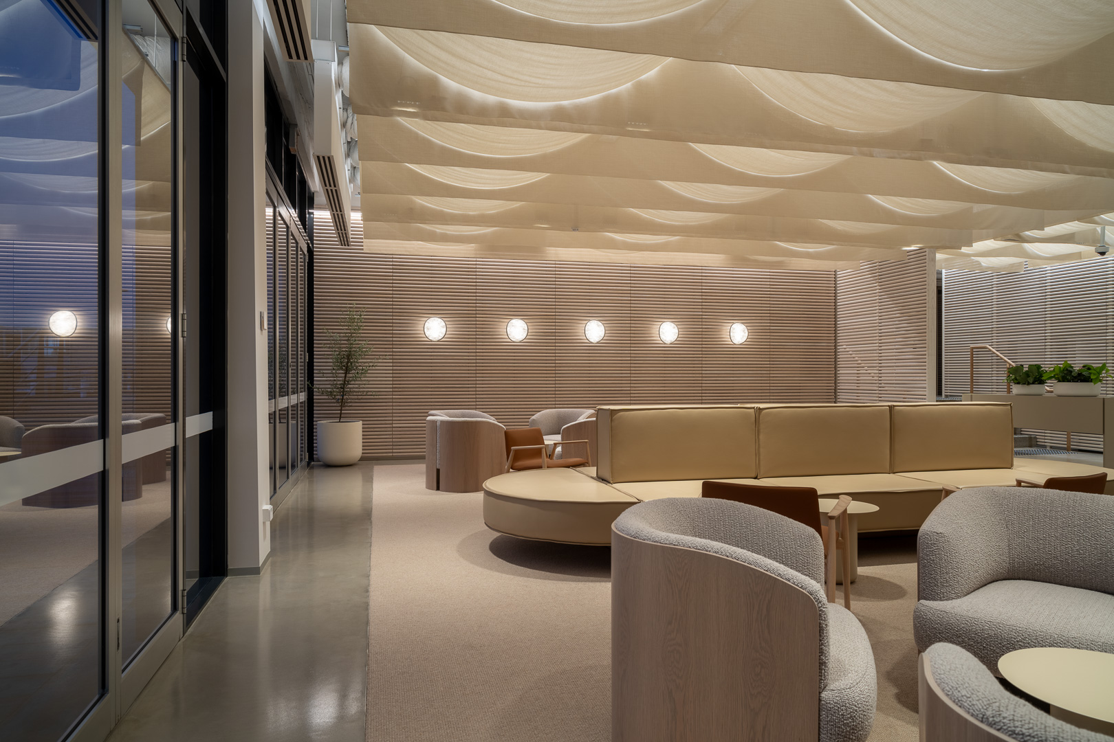 Interior space featuring modern seating under a draped ceiling, illuminated by recessed lights, creating a serene and inviting atmosphere.