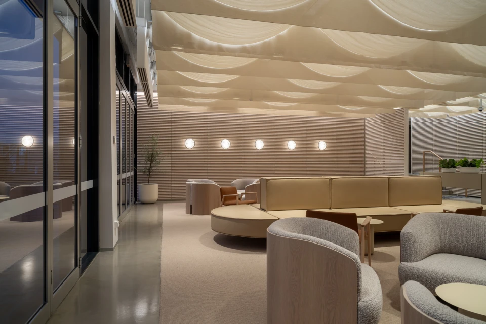 Interior space featuring modern seating under a draped ceiling, illuminated by recessed lights, creating a serene and inviting atmosphere.