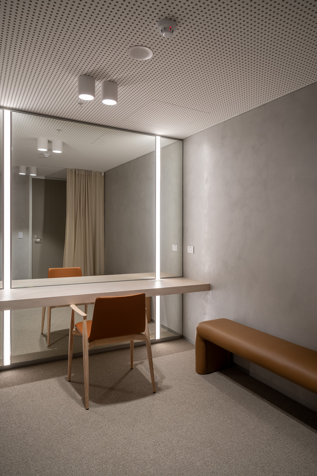 Minimalist dressing room with a chair, mirror, and bench. Neutral colors create a serene, modern space for fashion and personal care.