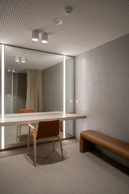 Minimalist dressing room with a chair, mirror, and bench. Neutral colors create a serene, modern space for fashion and personal care.