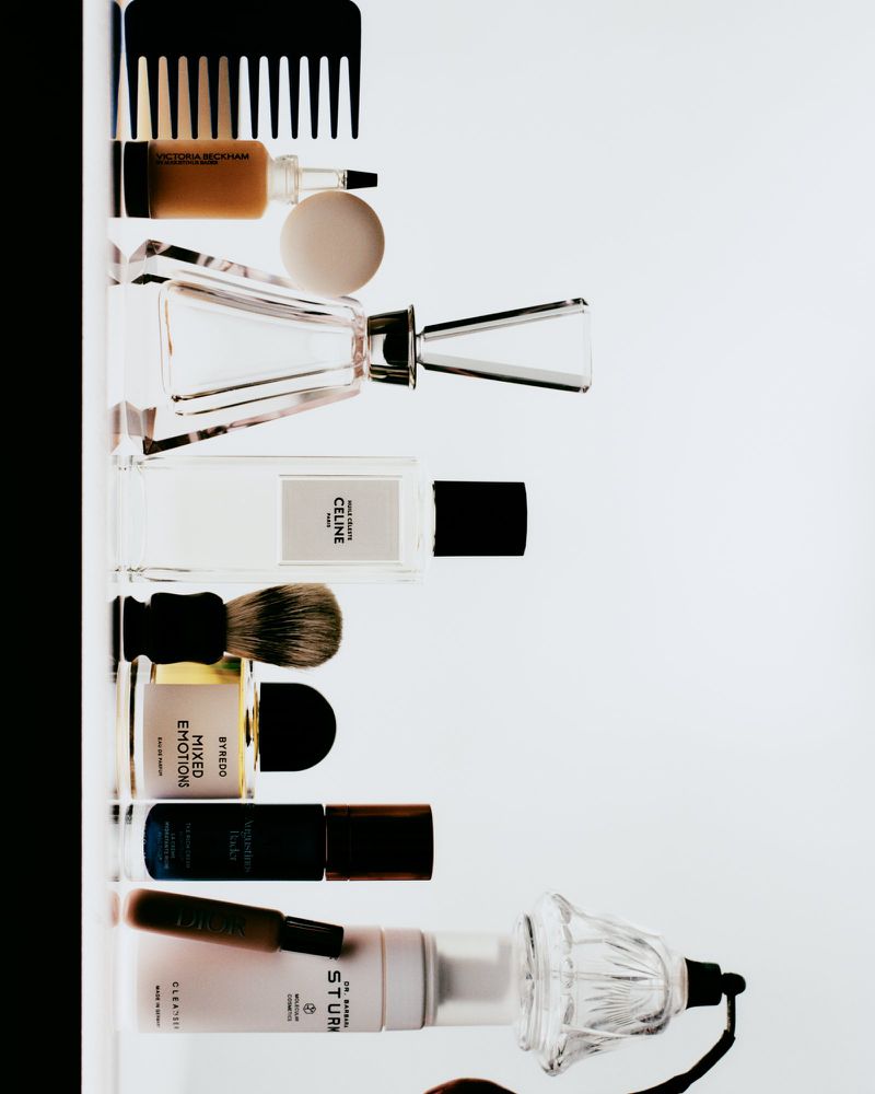 Collection of various cosmetic and beauty products including perfumes, creams, and brushes arranged on a clean white surface.