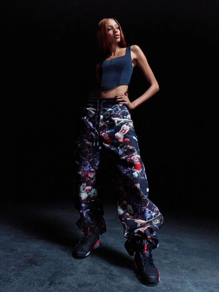 Model in dark crop top and patterned cargo pants posing against dark background for Nike Air Jordan Infrared Collection