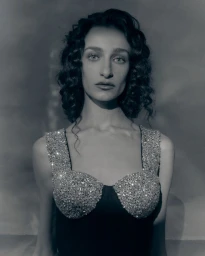 Portrait of a woman with dark curly hair wearing a crystal embellished dress for Patrick McDowell AW26 by Fran Gomez de Villaboa