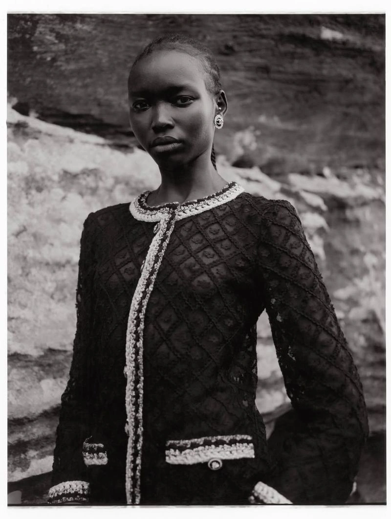 Model Amam Abit wearing a dark textured jacket against a rocky outdoor background for Blanc Magazine.