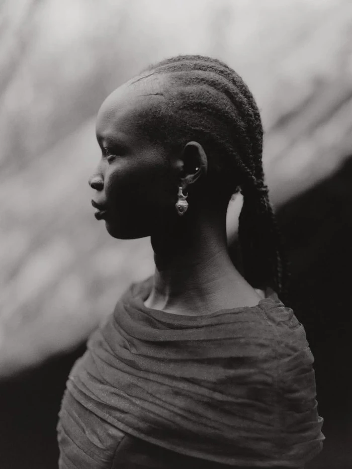 Profile portrait of a Black woman with braided hair and an earring wearing a draped garment for Blanc Magazine.
