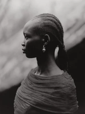 Profile portrait of a Black woman with braided hair and an earring wearing a draped garment for Blanc Magazine.