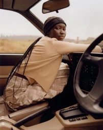Model Amam Abit in a cream sweater and headband seated inside a car for Blanc Magazine photographed by Oliver Oglesby