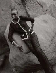 Model Amam Abit posing against large rocky boulders wearing a textured black patterned suit for Blanc Magazine.