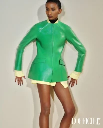 Model wearing a vibrant green jacket over a yellow shirt against a plain light neutral background for L'Officiel USA