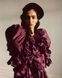 Model wearing a ruffled plum blouse and dark beret against a neutral wall for 72 Magazine True Romance editorial.