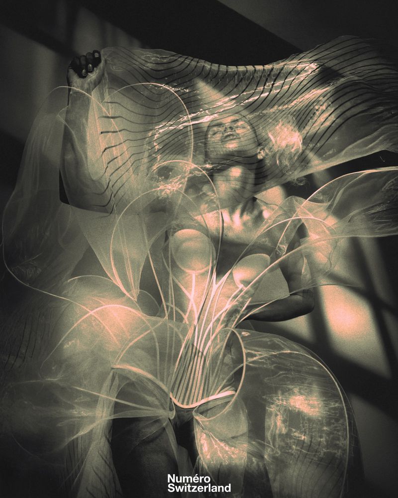 Artistic studio portrait of a woman with transparent draped material, posed in front of a dark background with visible text 'Numero Switzerland'.