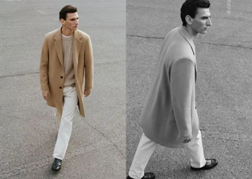 Man wearing a camel overcoat, cable-knit sweater, and white trousers walking on asphalt