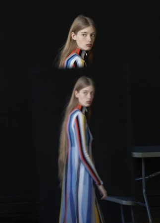 Woman poses in a striped dress in a studio with a black backdrop and a stool, captured in a fashion photography style with soft lighting.