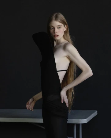 Portrait of a woman with long blonde hair wearing a sculptural black dress against a dark background for Modern Weekly China