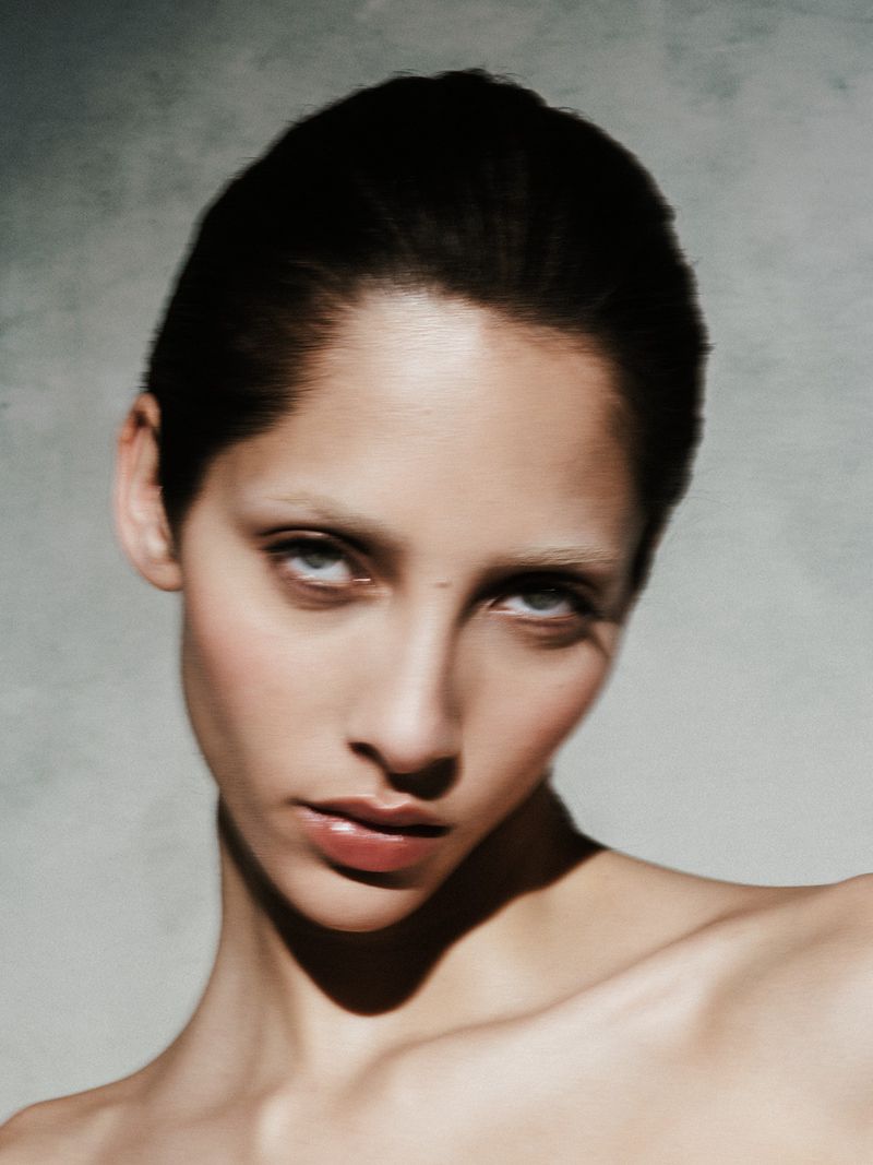 Striking beauty portrait of a young adult female with short dark hair, light skin, and intense gaze against a neutral backdrop.