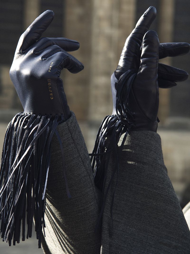 Leather fringed gloves. Closeup of a pair of black leather gloves with long fringe, against an out-of-focus urban background.