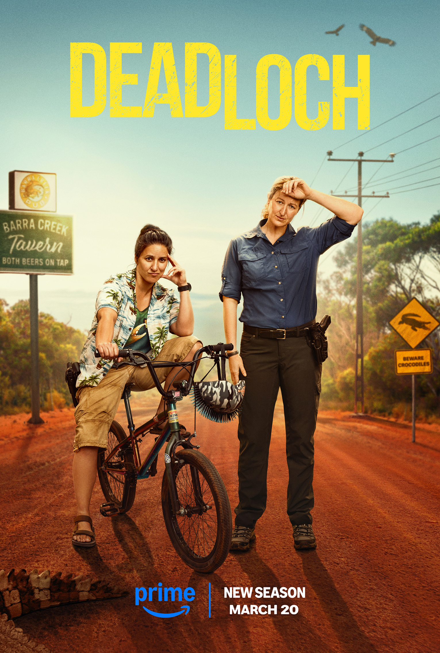 Promotional poster for Deadloch featuring two adult women standing on a road. One woman is on a bicycle and the other is standing.