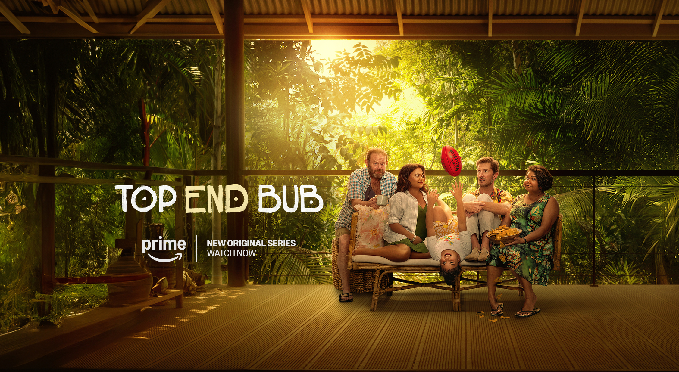 Group of five people sitting on a porch with tropical foliage in the background. Movie poster for "Top End Bub" on Prime.