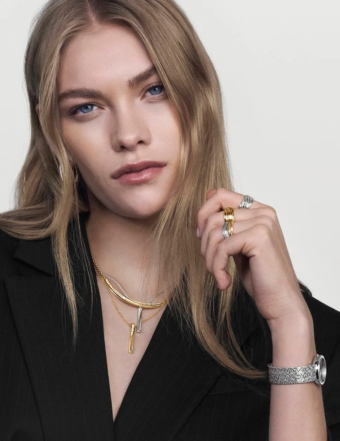 Model wearing gold and silver jewelry and a silver watch for Movado, photographed by Andrew Yee against a white background.
