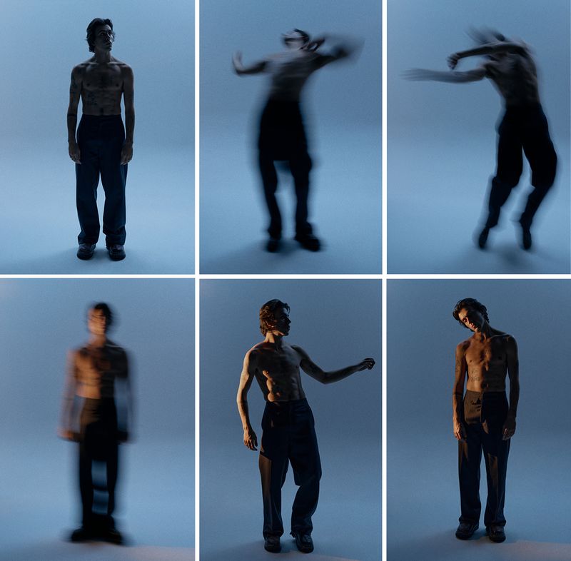Artistic arrangement of a slender male figure, shirtless with dark pants, set against a smooth grey background in a photo studio.