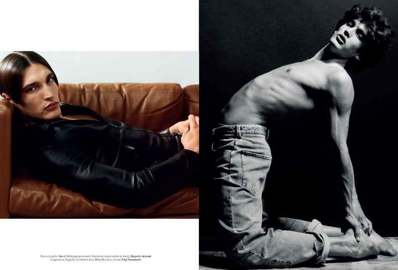 Fashion editorial shot of a male model reclining on a brown leather couch wearing a black leather jacket, and a male model kneeling in jeans.