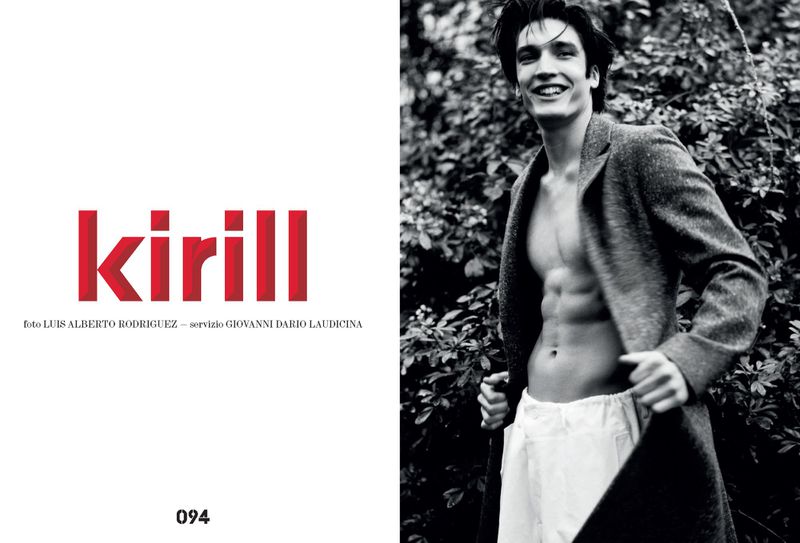A shirtless man in a jacket smiles in a monochromatic outdoor fashion shot featuring dense green foliage and red text on the left.