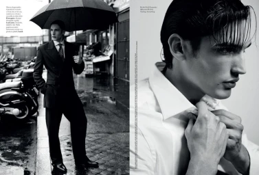 Black and white editorial spread featuring male model Kirill Karpenko in a tailored suit holding an umbrella and adjusting a white shirt.
