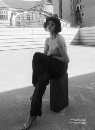 Model wearing sunglasses seated on a wooden block on a rooftop for an editorial by Stefan Dani in Elle Romania.