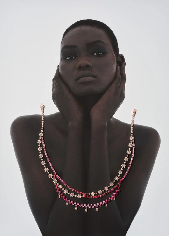 Model Ateta Jok with hands to her face wearing jeweled necklaces for 10 Magazine
