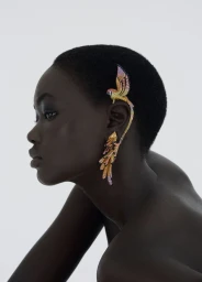 Model wearing ornate parrot ear cuff jewellery against a clean white background in profile view