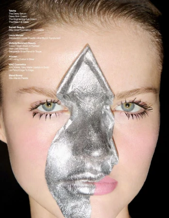 Close-up of a female model with silver foil makeup art covering half her face, against a dark background. Beauty shot showcasing silver foil.