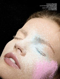 Close-up beauty portrait of a woman with closed eyes, covered in fine powder particles and colorful pigment on a dark background.