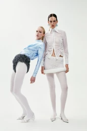 Two female models posing in avant-garde white and blue outfits against a seamless white background for Axis a Study About Balance