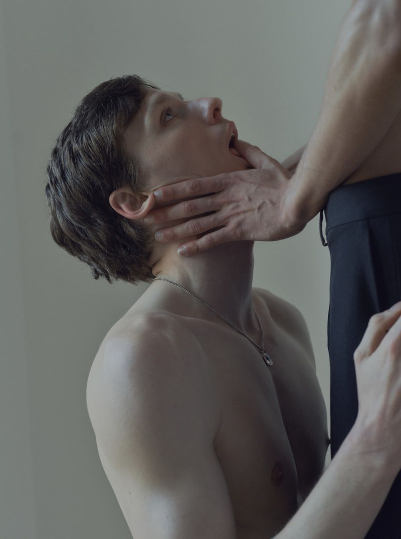 Close-up studio shot of a young adult with hands on face, highlighting a neutral color palette and intimate pose.